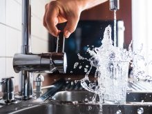 Personne en train d'activer un robinet de cuisine pour se servir une verre d'eau